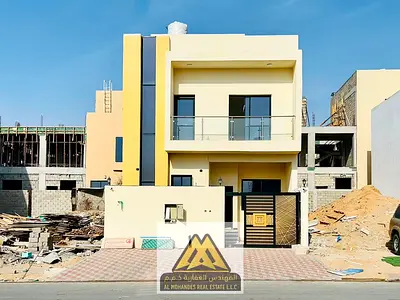 A premium townhouse for sale in Al Helio 1, Ajman, featuring two floors plus a rooftop. The property includes a front setback suitable for multiple ca