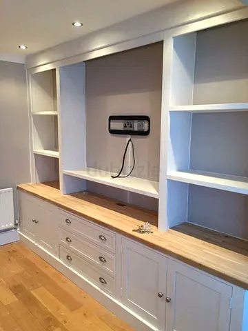 Built-in white wooden shelving unit with drawers and worktop
