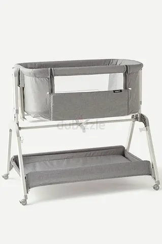 Grey bedside bassinet with storage shelf - gently used with a Rocking function & adjustable height.