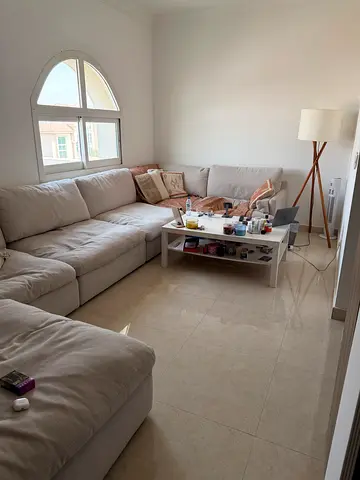 Large L-shaped beige fabric sofa with ottoman - good condition - cushions, table, and lamp included.
