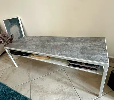 Simple modern coffee table with grey stone-look top and lower shelf. Can be used as a TV bench