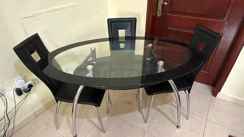 Glass top dining table with 4 black faux-leather chairs
