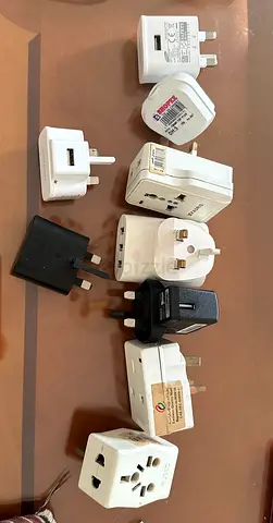 Collection of assorted international travel power adapters and plug converters - 20AED for all