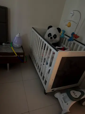 White wooden baby crib with mobile and mattress