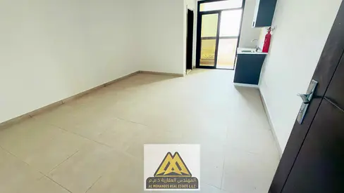 A spacious first-resident studio available for annual rent in Al Alia, Ajman. The studio features a distinctive balcony and a semi-separate kitchen, w