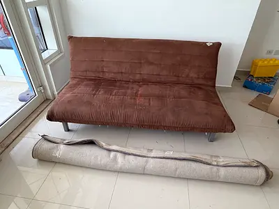 Brown futon sofa bed with rolled beige rug included