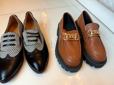 Two pairs of women's loafers - black patterned leather and brown chunky chain loafers
