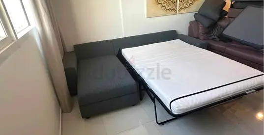 Grey L-shaped sofa bed with pull-out bed — good condition