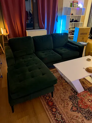 Dark green velvet L-shaped sofa with chaise and white modern coffee table