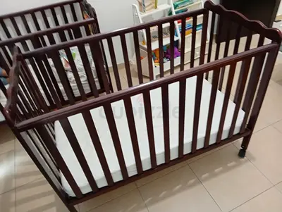 Wooden cot on wheels with mattress