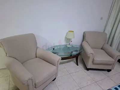 Pair of beige upholstered living room armchairs - with top glass table