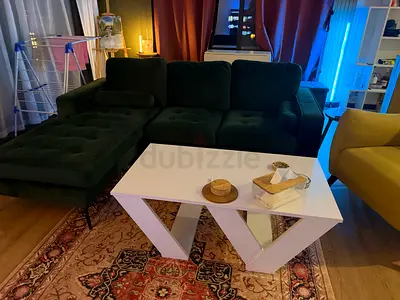 Dark green velvet L-shaped sofa with chaise and white modern coffee table