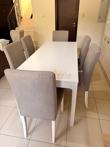 White dining table with 6 grey upholstered chairs