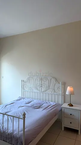 White Metal Frame Bed with Intricate Headboard، غرفة نوم
