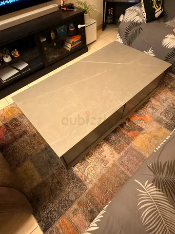 Modern rectangular coffee table with faux marble top and black base.