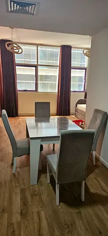 White rectangular dining table with 4 grey upholstered chairs