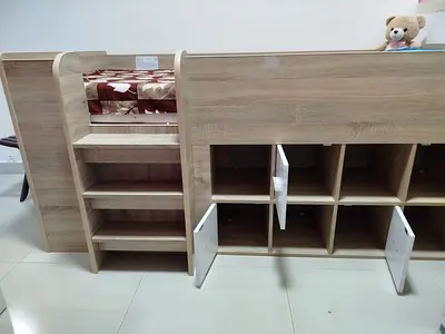 Wooden single loft bed with built-in storage shelves and cubbies