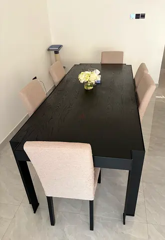 Solid black wood dining table with 6 beige upholstered chairs