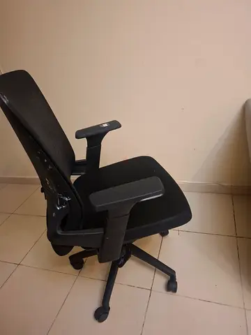Black ergonomic office chair with armrests and wheels.