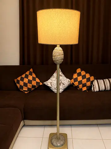 floor lamp with a gold/brass finish, intricate detailing, and warm beige lampshade.