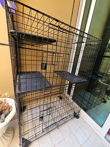 Large black metal dog crate with wheels and removable trays