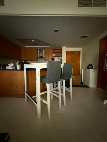 White table with two grey upholstered high stools .