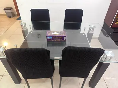 Modern glass top dining table with four black chairs