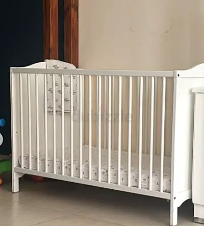 White wooden baby crib with mattress