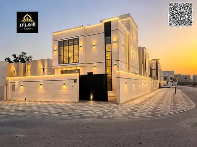 Villa for sale in Ajman, Al Helio area, including registration fees. It consists of 5 master bedrooms, a majlis, 2 living rooms, a maid's room, and a