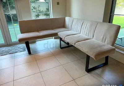 L-shaped beige upholstered corner banquet bench with metal legs