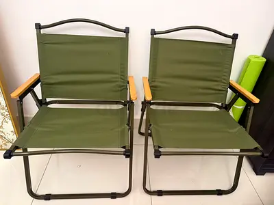 Pair of green folding outdoor chairs with wooden armrests