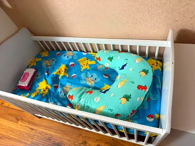 White Baby Crib with Pokémon-themed Bedding and Nursing Pillow