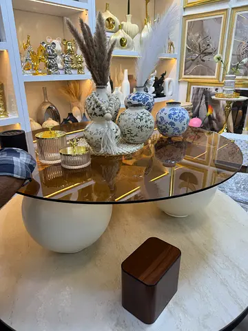 Round glass coffee table with sculptural cream bases