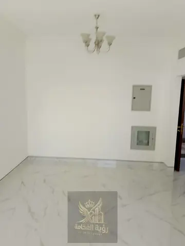 First-occupancy apartment for rent in Al Qasimia, Sharjah, featuring a bedroom and a living room. It offers a spacious layout, central air conditionin