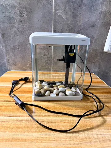 Small desktop aquarium tank with internal filter and pebbles