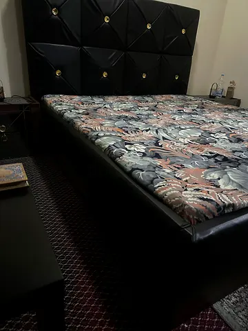 King Size leather bed frame with padded headboard and mattress included and two side tables.