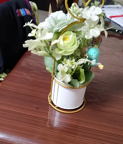 Small decorative artificial flower arrangement in ceramic pot with metal stand