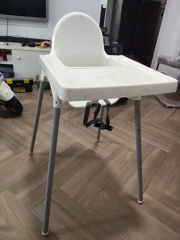 Simple white baby high chair with tray and safety straps