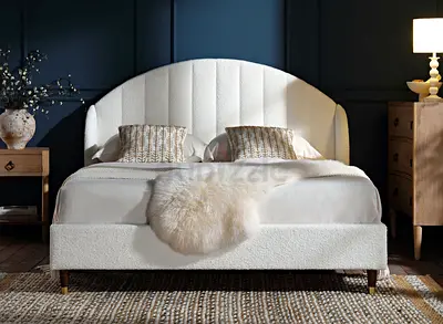 White upholstered double bed with curved headboard