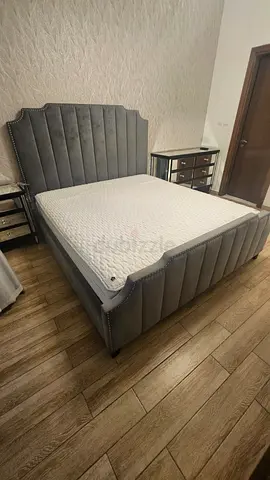 Grey upholstered queen bed frame with padded headboard