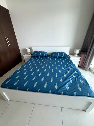 White wooden double bed frame with mattress and bedside tables