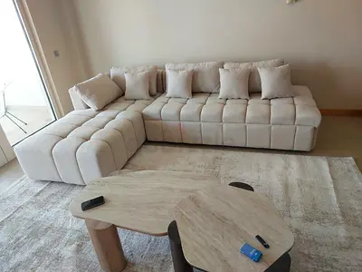Light beige L-shaped tufted fabric sofa with