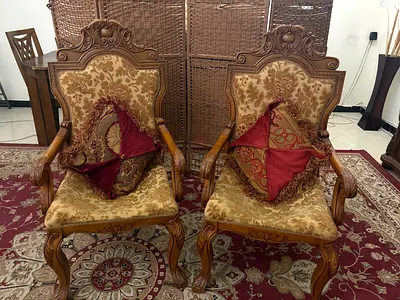 Pair of carved antique wooden armchairs with upholstered floral fabric