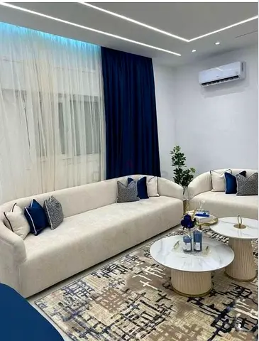 Modern neutral living room sofa set with patterned rug and marble coffee tables