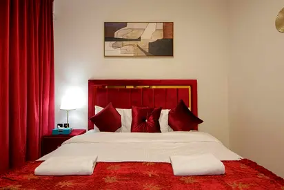Queen bed with red velvet headboard and matching bedding