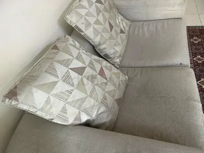 Light beige 2 seater fabric sofa with two patterned cushions - used