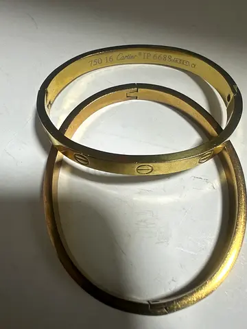 Two gold-tone bangle bracelets (one engraved, one plain) - preowned