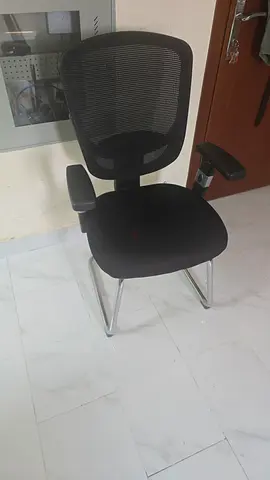 Black mesh visitor chair with fixed legs and armrests