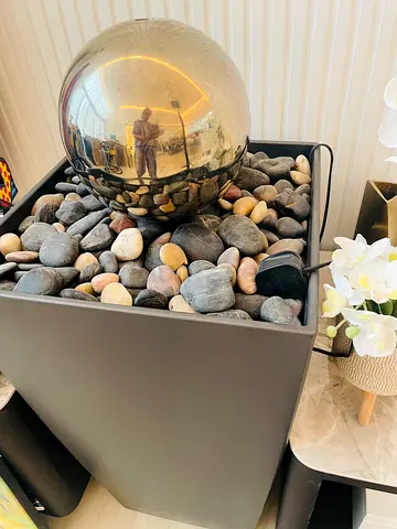 Modern indoor water fountain with decorative stones and reflective orb
