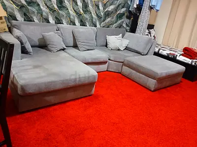 Large L-shaped grey fabric sectional sofa with ottoman